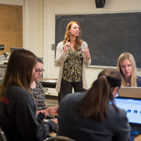 Professor instructs students working on their computers.
