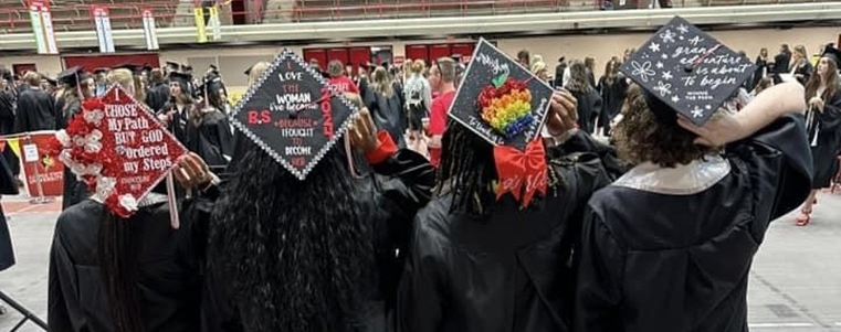 Four graduating students viewed from behind, displaying unique and personalized graduation cap designs