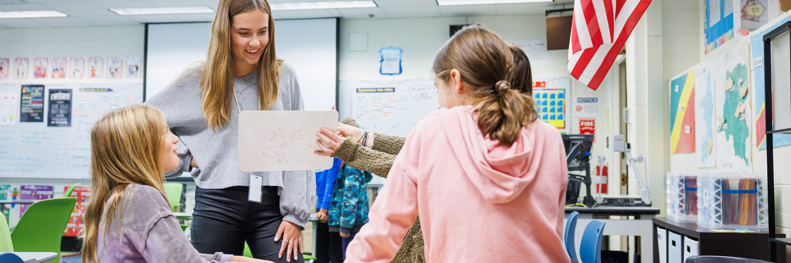 Students show their teacher a project they are working on.