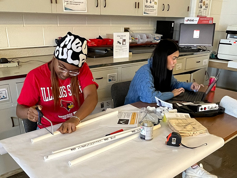 Two female students working together on an assignment in a classroom.