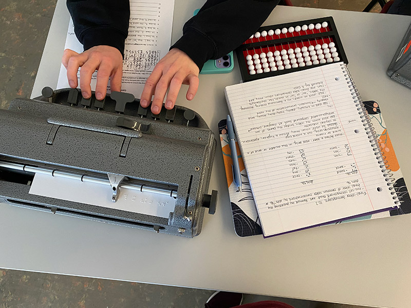 A person using a brailler typing machine.