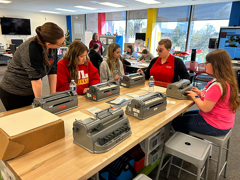 A team of girls using different brailler typing machine.