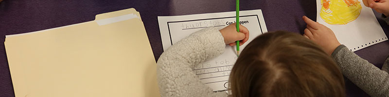 A small gril writing her name on a certificate