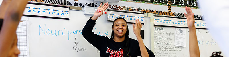 Teacher in front of the class with hands ups.