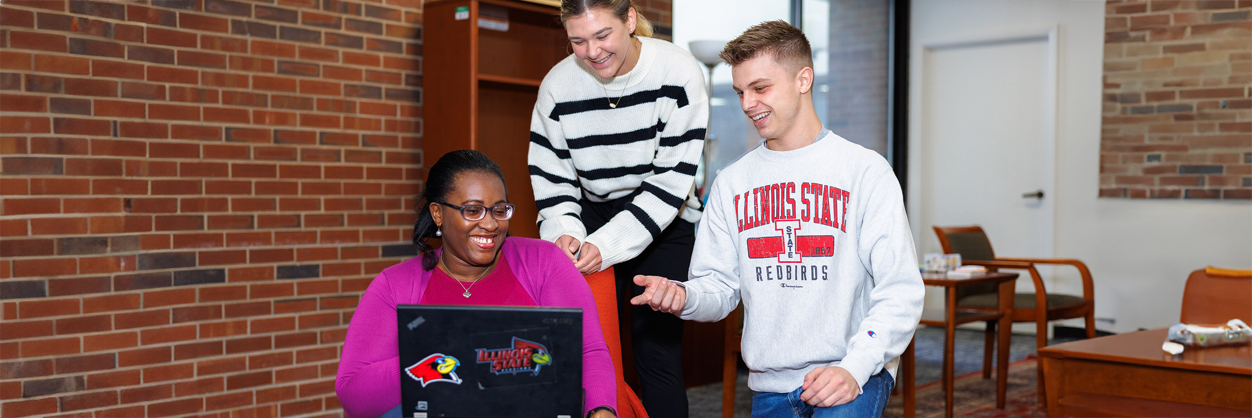 Group of students talking and looking at a laptop screen