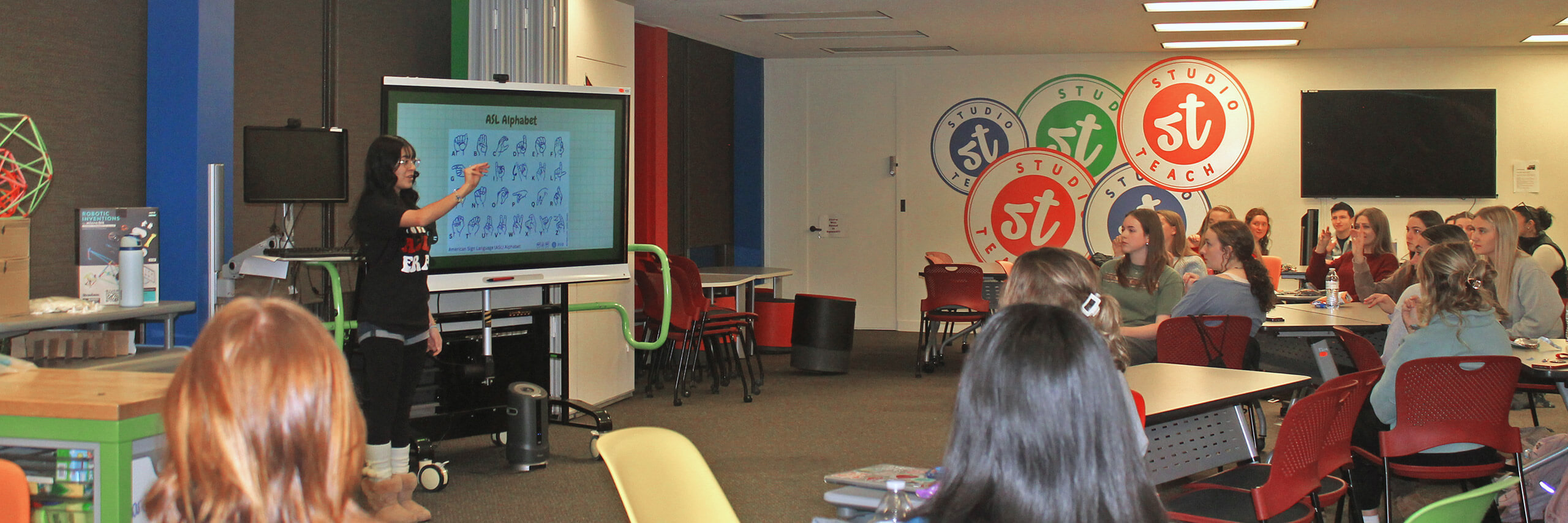 A professor teaching ASL alphabet to students